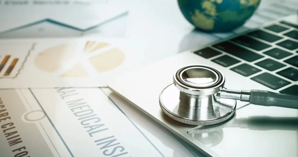 Health Insurance and Medical Coverage - Stethoscope on Laptop with Documents